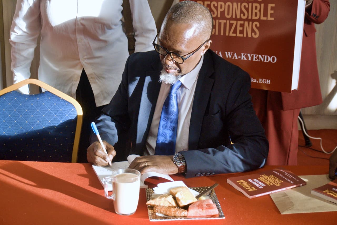 Eng. Mumina Wa-Kyendo signing a copy of his book